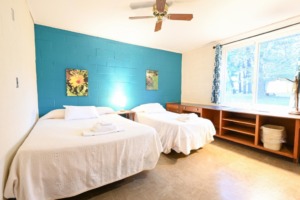 Sample lodge bedroom with two beds, large windows, and desk